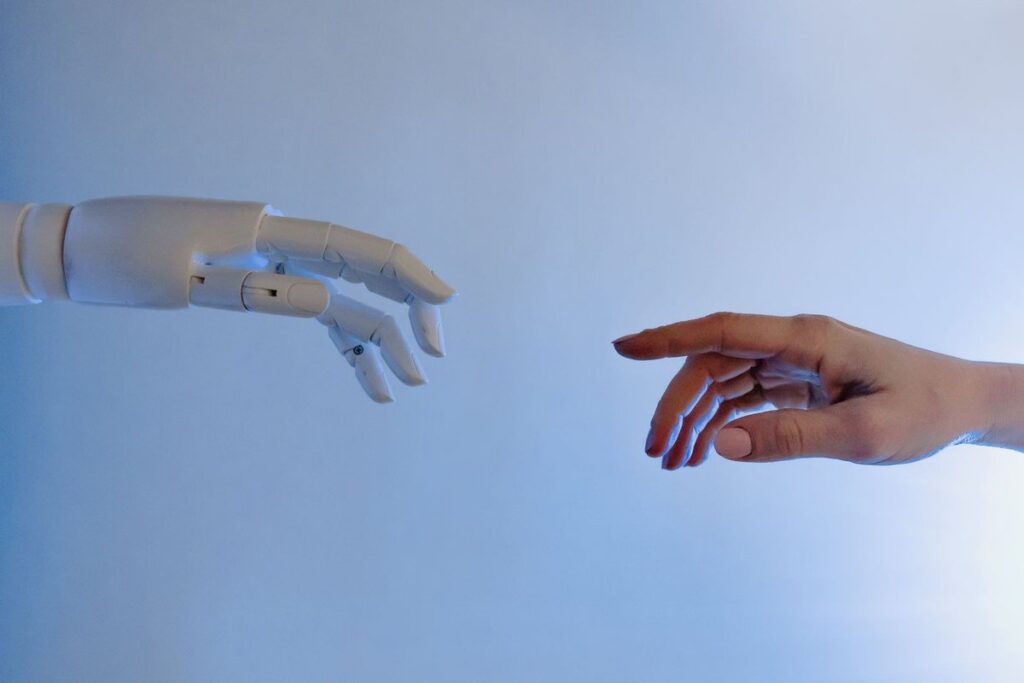 A human hand reaching toward a white robotic hand against a blue background