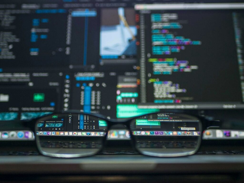 Eyeglasses in front of a monitor full of source code and developer tools