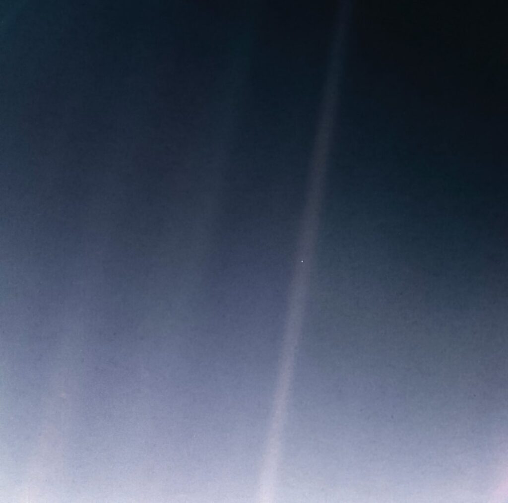 The Pale Blue Dot: Earth as a tiny speck in a band of scattered sunlight, photographed by Voyager 1 from about 6 billion km away (2020 reprocessed version)