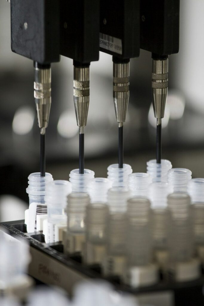 An automated lab machine dispensing DNA samples into rows of plastic vials