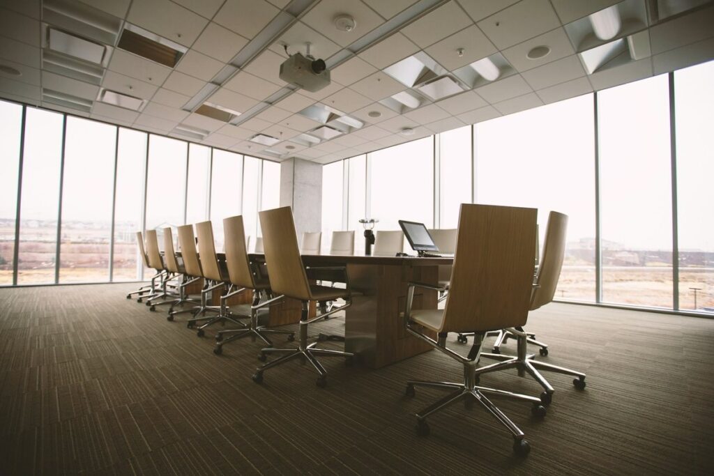 An empty corporate conference room with a long table, office chairs and floor-to-ceiling windows