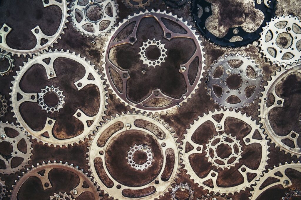 Interlocking metal gears and sprockets arranged across a rusted surface