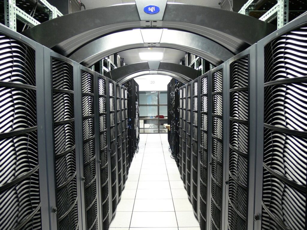 A long aisle between rows of server racks in a university data centre