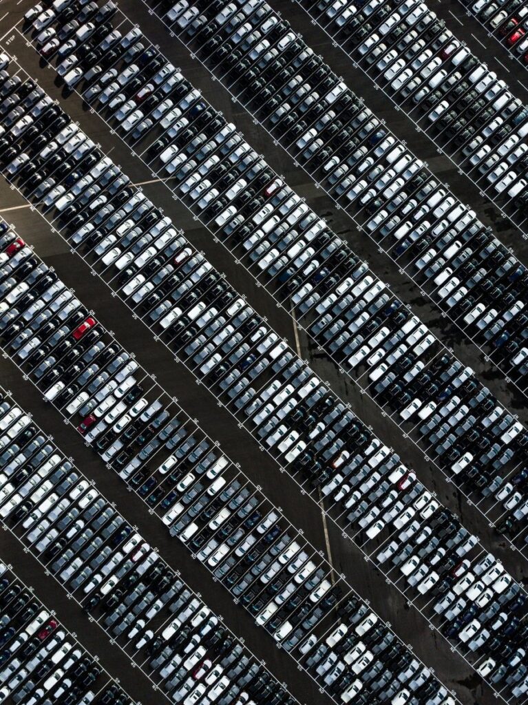 Aerial view of a vast car park, hundreds of cars lined up in neat diagonal rows