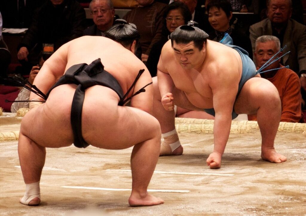 Two sumo wrestlers crouched at the starting lines for the initial charge of a bout at the January 2010 Tokyo tournament