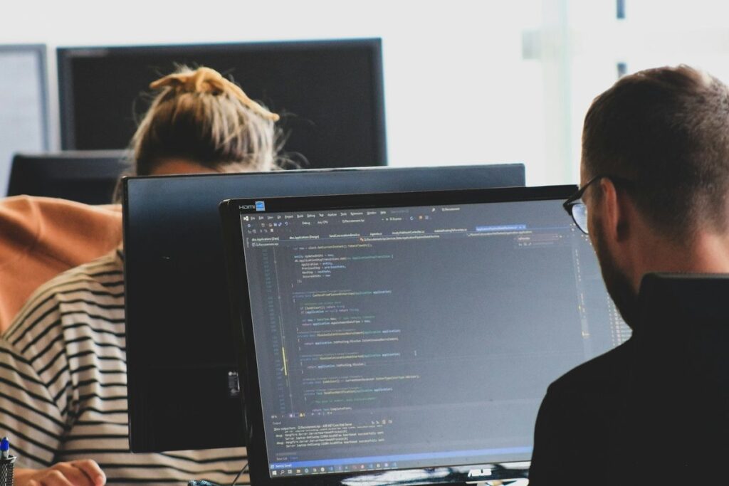 Developers seen from behind working on code in an IDE in a shared office
