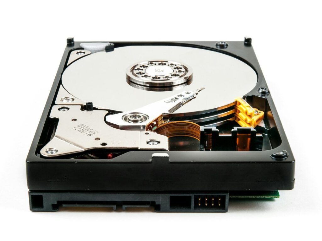 An opened hard disk drive showing its platter and read/write arm, the industry at the heart of the book’s case study