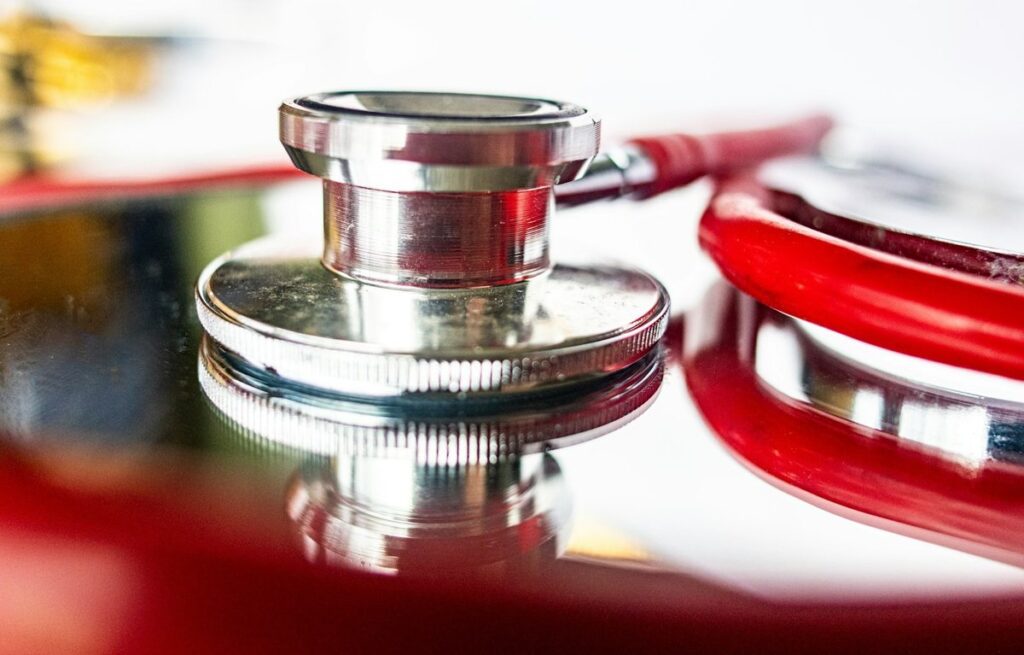 Close-up of a stethoscope chest piece with red tubing resting on a reflective surface