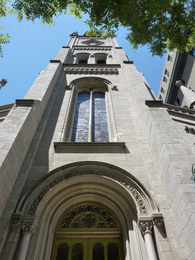 Looking up at the stone bell tower and arched entrance of Marble Collegiate Church on Fifth Avenue, New York, where Norman Vincent Peale preached